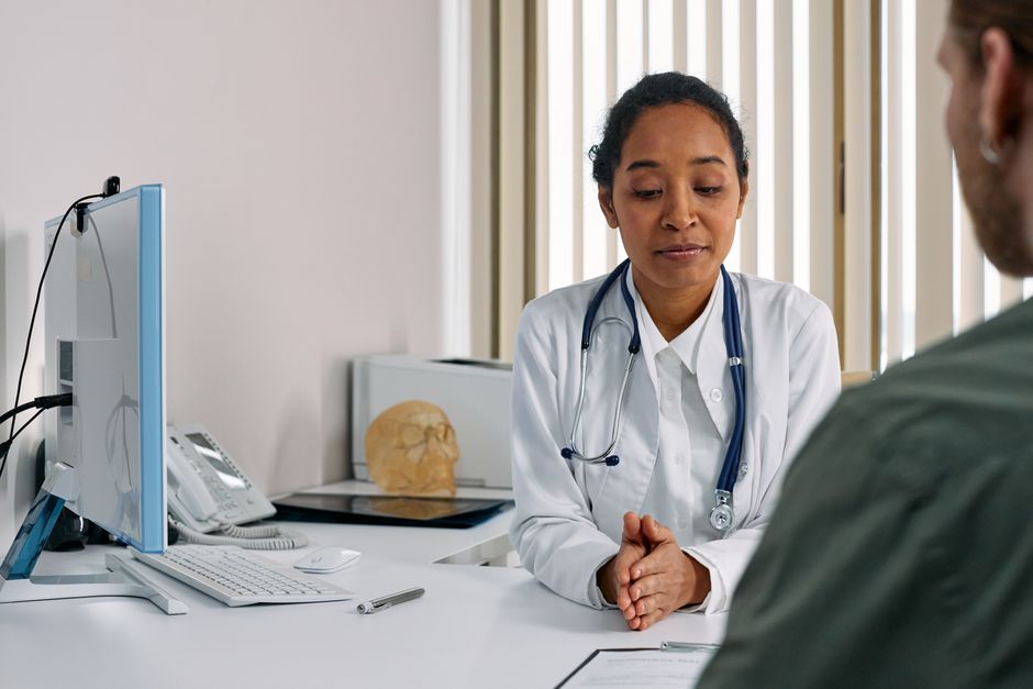 A family doctor listening to a patient at her desk